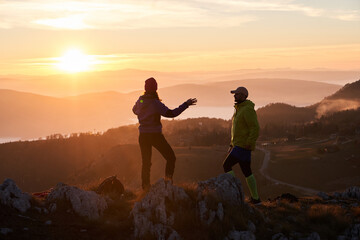 A joyful couple celebrates their victorious ascent to the mountain summit, embracing each other...