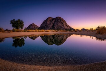 Desert mountain reflection in tranquil pool at sunrise