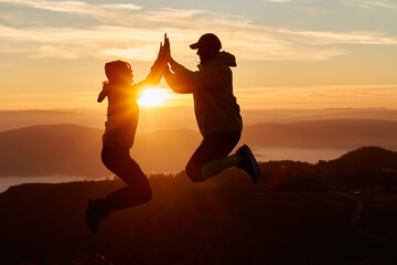 A joyful couple celebrates their victorious ascent to the mountain summit, embracing each other...