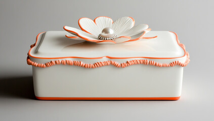 White rectangular pot with orange trim, flower-shaped lid with coral accents, and pearl embellishment in the center.