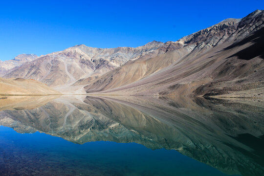 Reflections of solitude&mdash;barren mountains mirrored in a tranquil lake.