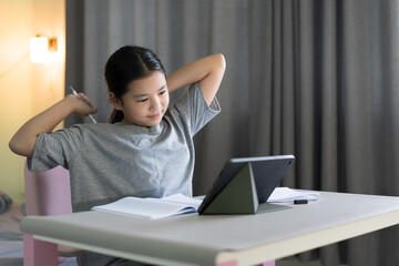 asian child smile learning study online class on computer tablet or kid girl student studying and tired stretch oneself or young woman people learn from home school by video call technology education