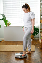 Woman checking weight on bathroom scale in at home