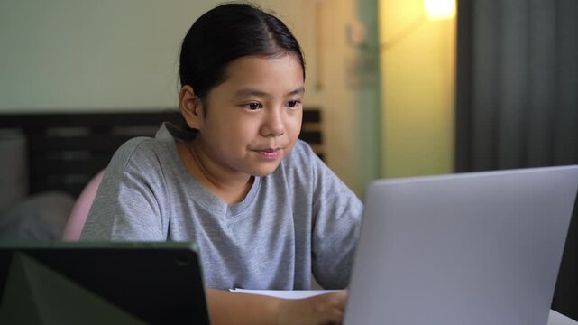 asian child smile learning on computer laptop typing by study online class or kid girl student fun studying by notebook or young people happy learn from home school by tablet technology education