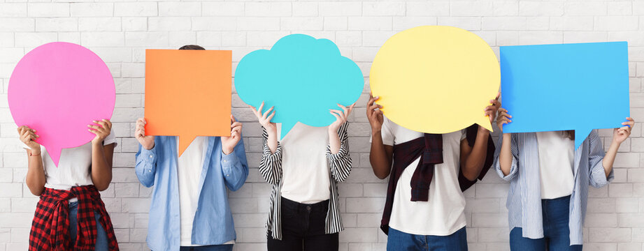 Teenagers holding empty speech bubbles, over white wall, crop