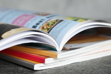 Stack of different magazines on grey table, closeup