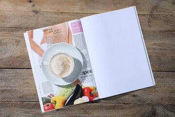 Open magazine and coffee on wooden background, top view. Mockup for design