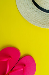 Flatlay, summer vacation. Hat and sandals on a yellow background. Vertical background.
