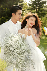 Joyful couple celebrating with flowers in a sunny garden.