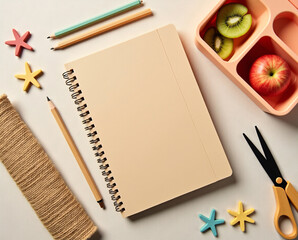 Flat lay of zero-waste school supplies for kids: kraft paper notebook, wooden pencils, jute pencil case, bamboo-handle scissors, handmade decorations, and fruit lunchbox.
