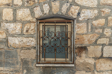 window with decorative rusty metal grille in an old stone building