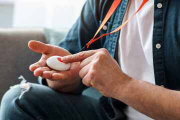 Unrecognizable senior man pushing panic button on emergency equipment for elderly people, cropped. Closeup of man's hand pressing alarm button for emergency hung on his chest, copy space