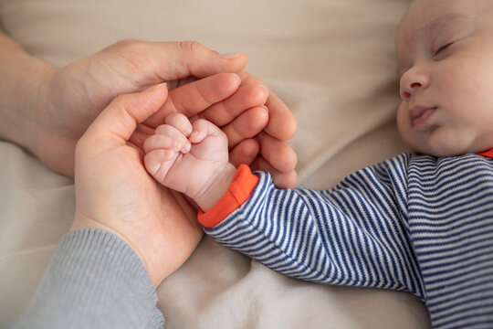 A close-up of adult and baby hands. A tender moment with hands. A baby's hand in an adult's. A symbol of love and care. The hands show connection and warmth. Family and baby time.