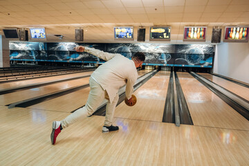 Fototapeta premium Running and throwing a ball. Man is playing bowling indoors