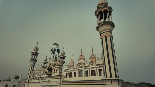 Grand mosque in Chicha Watni, Pakistan, featuring tall minarets, domes, and a moonlit evening sky