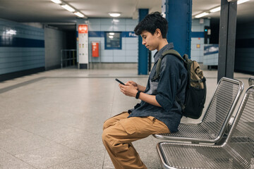 Young student girl using smartphone while waiting for subway train
