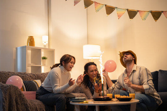 Friends celebrating birthday at home with sparklers and balloons