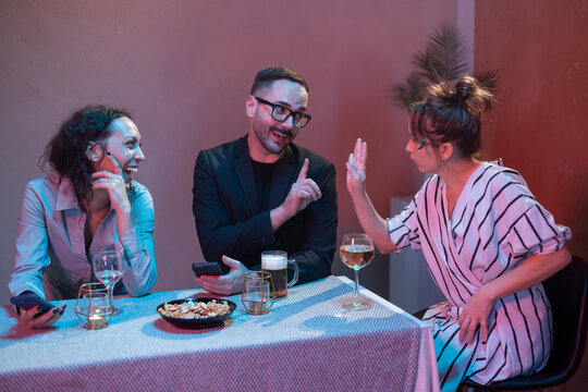 Friends having fun at a bar, drinking and using smartphones - Powered by Adobe