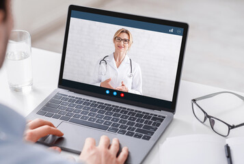 Modern treatment at home. Man watches at laptop with video woman doctor and gets consultation, close up, free space