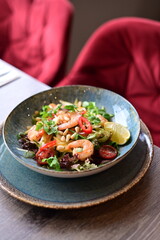 Background view of a gourmet shrimp salad with vegetables and mango, elegantly served on a table in a restaurant. A fresh and colorful dish, ideal for healthy dining