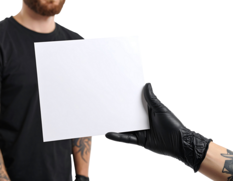 A person wearing a black glove is holding a blank white sheet of paper against a dark background. A person in a black t-shirt is partially visible in the background. Studio lighting is used, and the