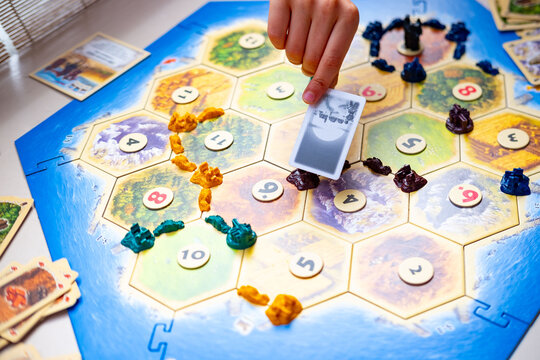 Playing popular strategy classic Catan board game, family enjoys quality time, Catan game tiles players plan moves in exciting tabletop competition, happy Family moment