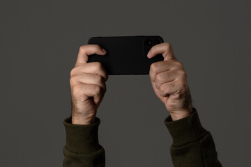 Hands Holding Smartphone Horizontally On Grey Background