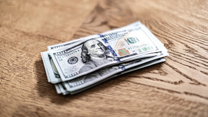Stack of cash placed on rustic wooden table, symbolizing financial success and importance of money management. US dollar currency.