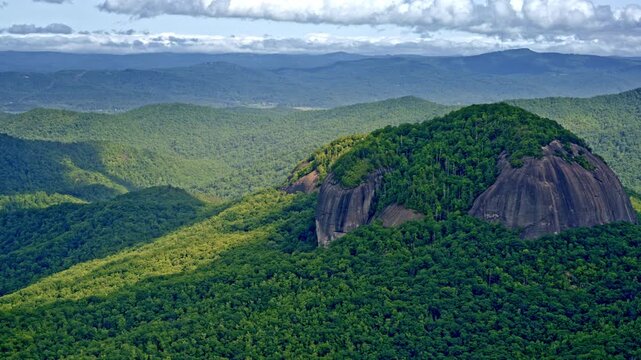 Sweeping drone shot of a towering, stand-alone mountain detached from the main range.