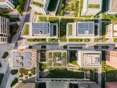 Aerial view of rooftops adorned with solar panels and lush greenery, a harmonious blend of technology and nature, Village des Athl&Atilde;&uml;tes Olympiques, &Atilde;Žle-de-France, France.