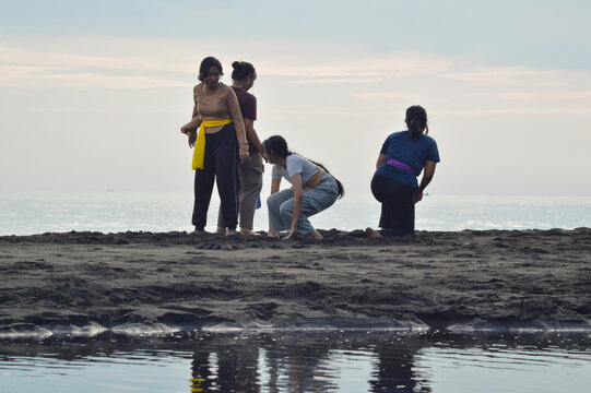 The teen girls rise from the sand, laughing and brushing off after an amusing fall during their beach yoga session.