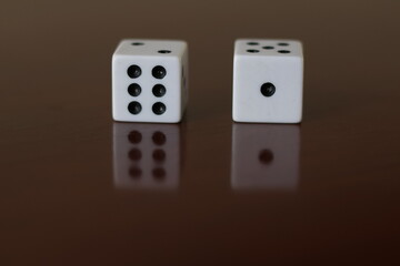 Una toma de cerca  de uno o varios dados blancos para juego en una mesa de color marrón oscuro como fondo