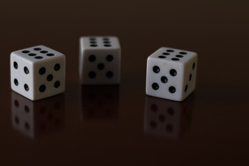 Una toma de cerca  de uno o varios dados blancos para juego en una mesa de color marrón oscuro como fondo