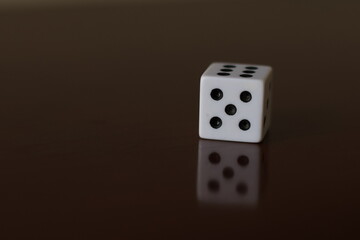 Una toma de cerca  de uno o varios dados blancos para juego en una mesa de color marrón oscuro como fondo