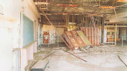 View of the earthquake-ravaged Ukedo Elementary School, where twisted metal and debris litter the floor under a collapsed ceiling, a stark reminder, Ukedo, Fukushima, Japan.