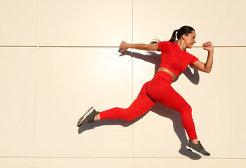 Woman in sportswear running near building outdoors, space for text