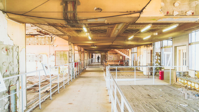 View of a desolate, earthquake-ravaged school corridor, illuminated by stark fluorescent lights against the backdrop of destruction, Ukedo Elementary School, Namie, Fukushima, Japan.