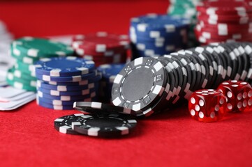 Casino chips, playing cards and dice on red table, closeup