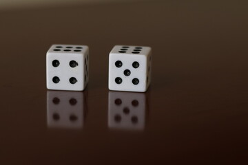 Una toma de cerca  de uno o varios dados blancos para juego en una mesa de color marrón oscuro como fondo