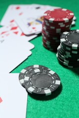 Casino chips and playing cards on green table, closeup