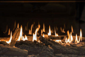 Burning gas fireplace with firewood close-up