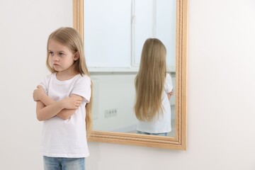 Upset little girl near mirror at home