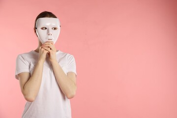 Anonymity. Woman wearing mask on pink background, space for text