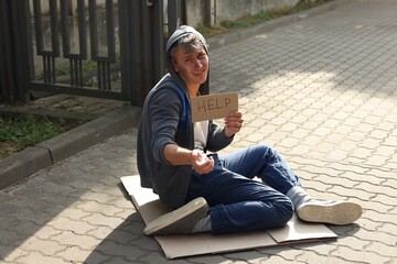 Homeless man with sign Help begging for money on carton outdoors