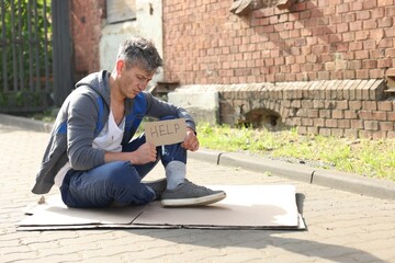 Homeless man with sign Help on carton outdoors, space for text