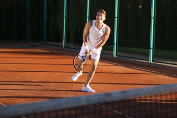 Fototapeta premium Young man playing tennis at court on sunny day