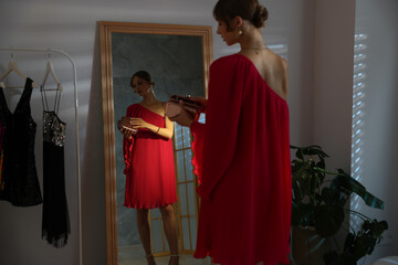 Beautiful woman with stylish bag getting ready near mirror indoors
