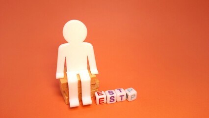 Plastic blocks spelling "ESTP," with a small toy figure and a magnifying glass. ESTP is one of the 16 personality types identified by the Myers-Briggs Type Indicator or MBTI.