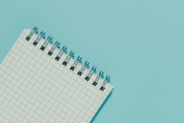 Top left of a blank, spiral bound grid notepad on serene blue with ample space. Conveys planning, design, writing, learning, and fresh starts with a minimalist aesthetic.