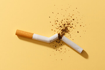 Broken cigarette with tobacco scattered on yellow background, stop smoking concept, anti tobacco health awareness